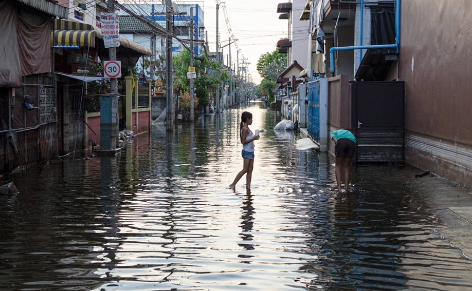 Thailändisches Mädchen auf überfluteter Straße