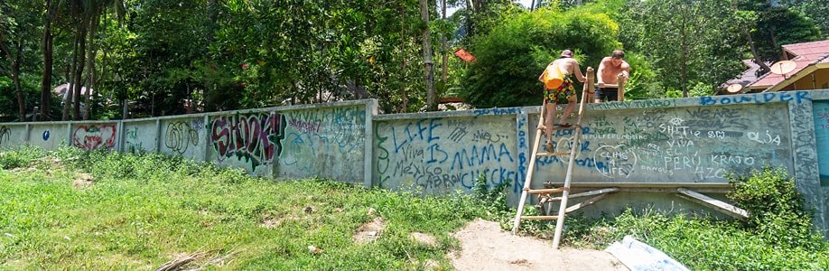 Zwei Jungs steigen über die Mauer Richtung Railay East Beach.